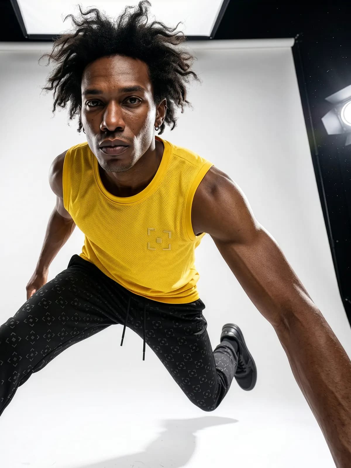 Model in a yellow tank top jumping in a studio light box